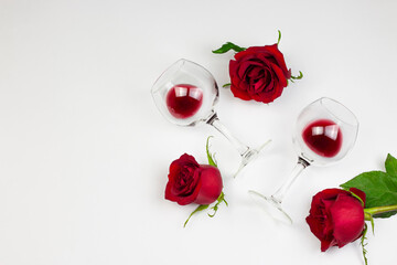 Red roses and wine glasses with red wine on white background. Holidays and Valentin’s day...