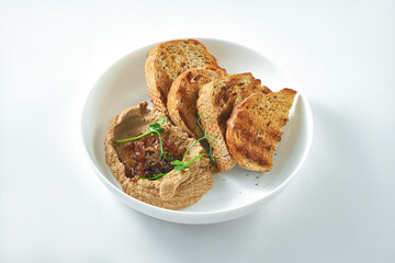 An ideal appetizer - chicken liver pate with caramelized onions and rye bread in a white plate on a white background