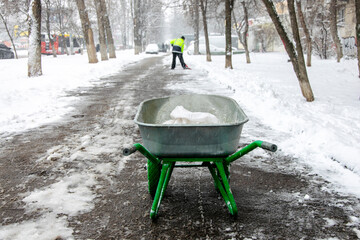 A janitor cleans the sidewalk and sprinkles salt.