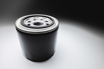 Black new oil filter in contrasting light on a black and white background. Wide angle