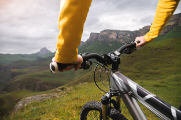 Close-up of female hands holding the handlebars of a mountain bike in the summer in the mountains