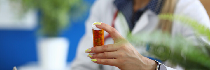 Close-up of doctor hand holding capsules in tube. Practitioner prescribing pills to increase...