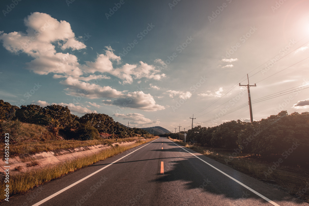 Wall mural Empty asphalt road through the green field and clouds on blue sky.