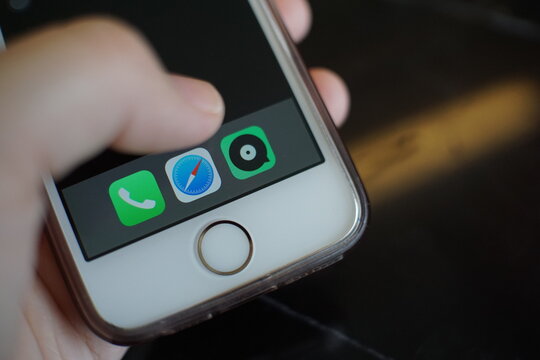 Chon Buri,Thailand/Chon Buri  April 13, 2019 :Mobile phone in a women hand ,thumb finger selecting JOOX Music application on home desktop with iPhone SE.