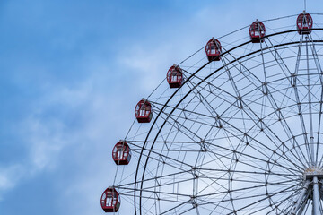 Ferris wheel on blue cloudy sky background