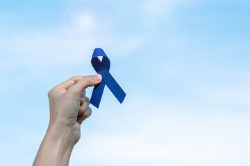 March Colorectal Cancer Awareness month, Woman holding dark Blue Ribbon for supporting people living and illness. Healthcare, hope and World cancer day concept