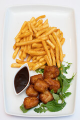 French fries with salad and meatballs on white plate