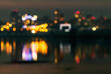 Fototapeta premium Night bokeh light in big city view with its reflection in river water, abstract blur defocused background