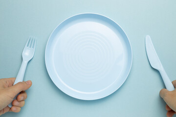 Fork, knife and empty plate on sky blue background. flat lay, top view, copy space