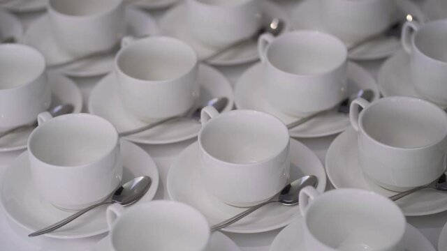 A lot of empty white cups or mugs plates are on the table. The concept of hot coffee and tea