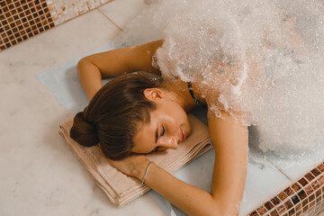 Luxurious relaxing foam massage in the Turkish hammam. Masseur crumples woman's skin in hammam - obrazy, fototapety, plakaty