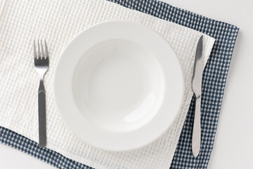 White empty plates set on the table with knives and forks and tablecloths. Ready to eat