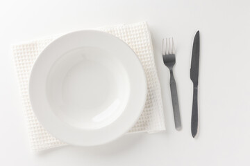 White empty plates set on the table with knives and forks and tablecloths. Ready to eat