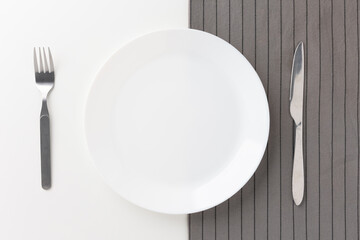 White empty plates set on the table with knives and forks and tablecloths. Ready to eat