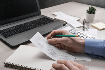 Man hand using calculator and writing make note with calculate about cost and taxes at home office. Businessman doing some paperwork in the workplace