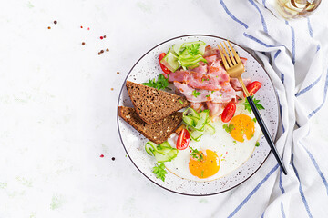 English breakfast - fried egg, bacon, tomatoes  and bread. Top view, flat lay, overhead