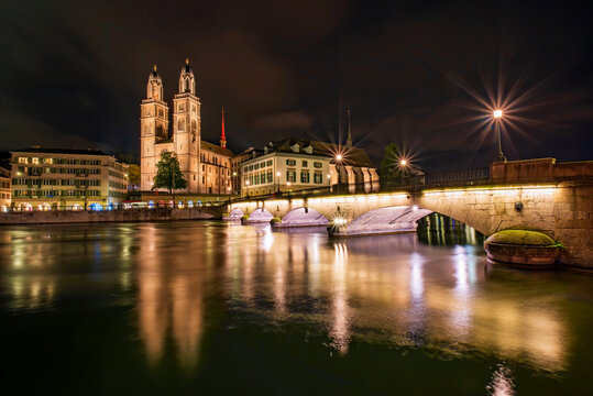 Picturesque night view of Grossmuenster church, town hall and Minster Bridge across Limmat river in Zurich, Switzerland