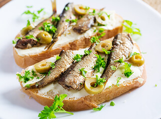 Sandwich - smorrebrod with sprats, green olives and butter on wooden table. Danish cuisine.
