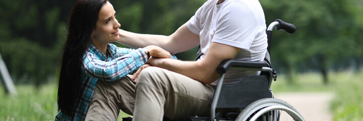 Portrait of sweet couple spending time together on fresh air in park. Lovely woman and man chatting and hugging. Happy relationship and disabled people concept