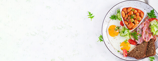 English breakfast - fried egg, beans, bacon, tomatoes  and bread. Top view, banner, overhead