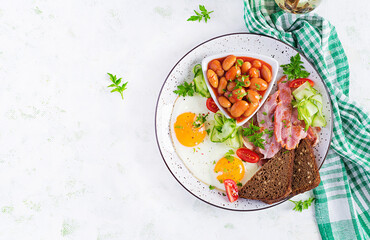 English breakfast - fried egg, beans, bacon, tomatoes  and bread. Top view, flat lay, overhead