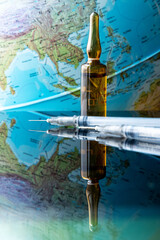 Vaccinate and save the world. A set of vaccine, syringe and lab equipment in front of the globe. Beginning of mass vaccination in the light of the global pandemic of covid-16, coronavirus.