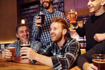 Soccer fans celebrating victory. Group of people together indoors in the pub have fun at weekend time