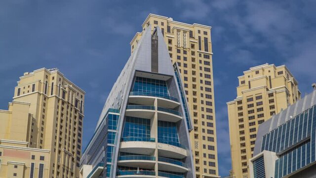 Dubai Marina towers reflected in water from promenade timelapse hyperlapse, United Arab Emirates. Dubai Marina is a district in Dubai and an artificial canal. Blue cloudy sky