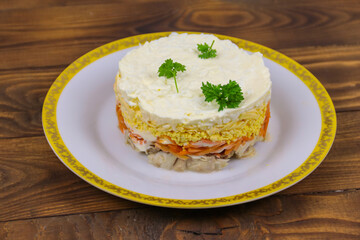 Tasty layered salad with chicken, carrot, eggs, cheese and mayonnaise on wooden table