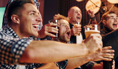 Soccer fans celebrating victory. Group of people together indoors in the pub have fun at weekend time