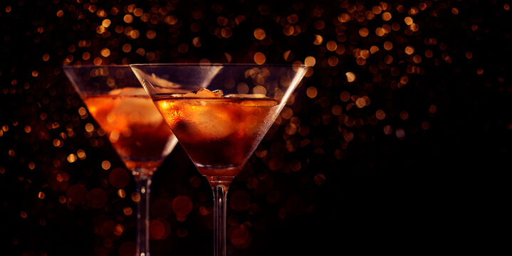 Two martini glasses in front of red bokeh background. Luxury cocktail drink in restaurant bar with night lights blur. Classy beverage celebration party for new year, christmas, valentine.
