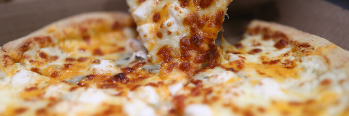 Close-up of persons hand taking delicious slice of oven baked pizza. Bacon sausages double cheese spices and tomato. Yummy quick lunch. Unhealthy brunch. Homemade traditional italian food concept