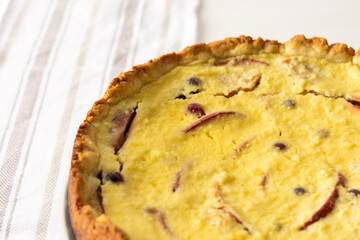 Delicious sweet cheese pie with apples and cranberries, fruit and berry curd pie on a white background with a kitchen towel