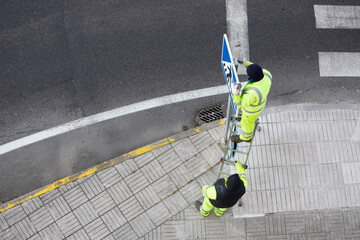 Workers installing a new road sign on street sidewalk