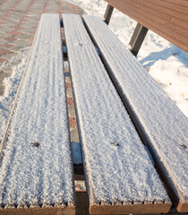 Wooden bench covered with snow.