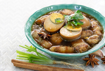 Thai Stewed belly pork and eggs with spices in green bowl on napery Thai food thai called  “Palo