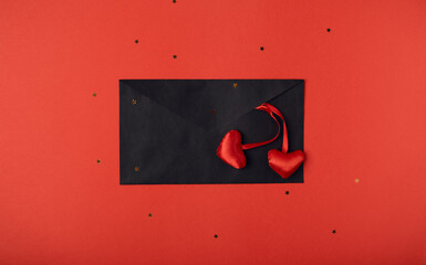Black envelope and red hearts on the red background. Romantic love letter for the Valentine's day concept. Space for text.