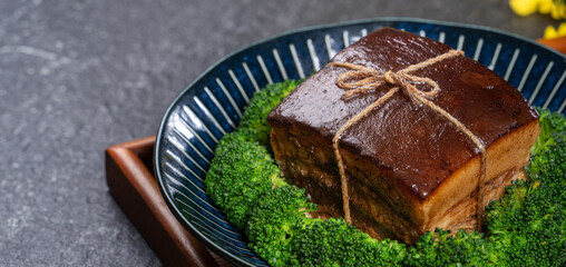 Dong Po Pork meat in a blue plate with broccoli in black background.