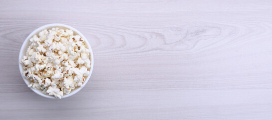 Salted popcorn in a bowl on a wooden table. Top view