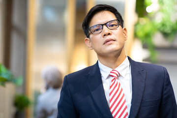 Portrait Asian man in suite drinking coffee and working on laptop computer at the modern office.