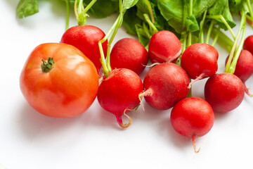Fresh radish with tops and tomato on a white background