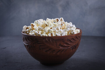 Salted popcorn in a bowl on a table on a gray background. Front view