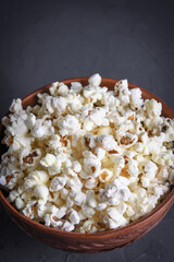 Salted popcorn in a bowl on a table on a gray background. Front view