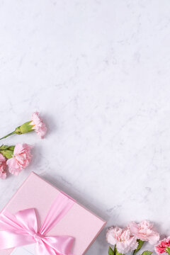 Top view of beautiful carnation and gift on marble white table background.