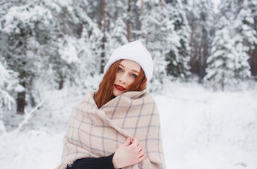Obraz premium a girl with bright red hair stands in a snowy forest.