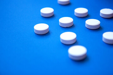 Set of white pills on blue background. Pills background. White tablets on a blue background