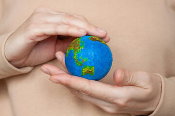 Model of the planet earth in female hands. Fingers hold and protect the globe. 