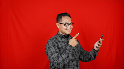 Wow face of Asian man shocked what he see in the smartphone isolated red background
