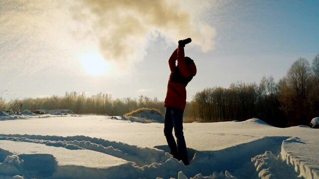 The young man, with a sharp wave of his hand, pours hot water from a cup. The paradoxical "Mpemba effect". Effect of the blast of frosty smoke signal