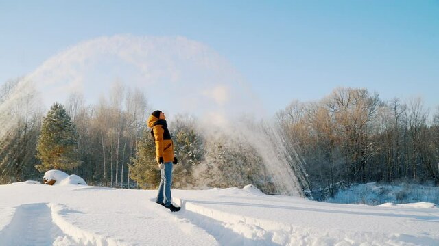 The young man, with a sharp wave of his hand, pours hot water from a cup. The paradoxical "Mpemba effect". Effect of the blast of frosty smoke signal